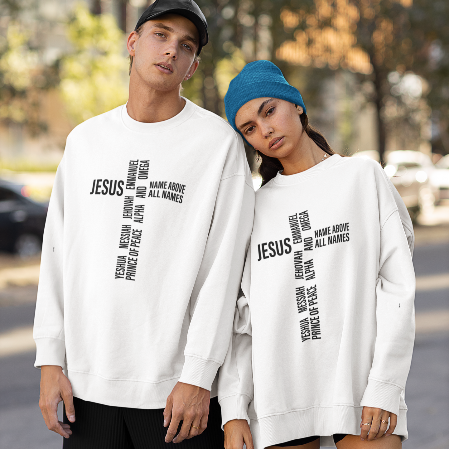 Two people wearing white sweatshirts with text on a street.